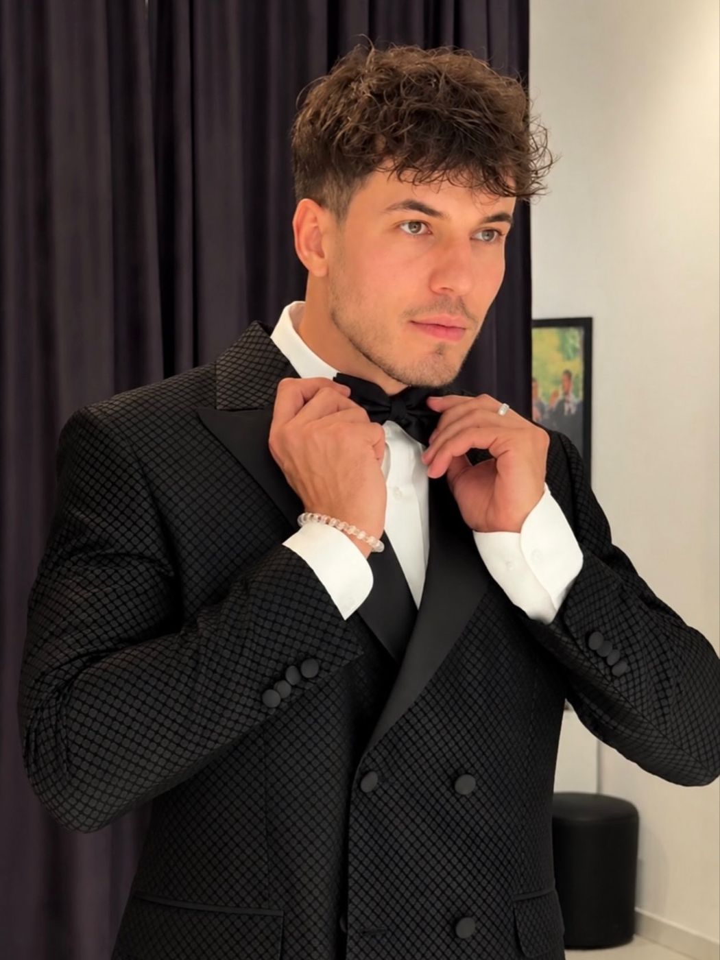Klodian Mihaj adjusting his bow tie in a black tuxedo